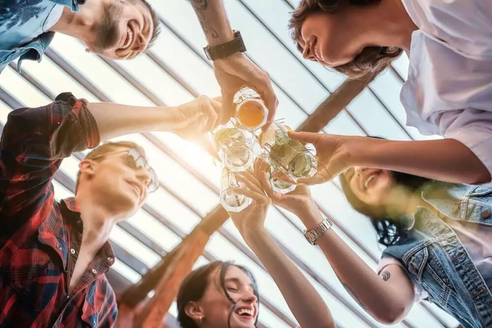 Mozrest - Group of friends smiling and cheering with glasses on a restaurant's terrace