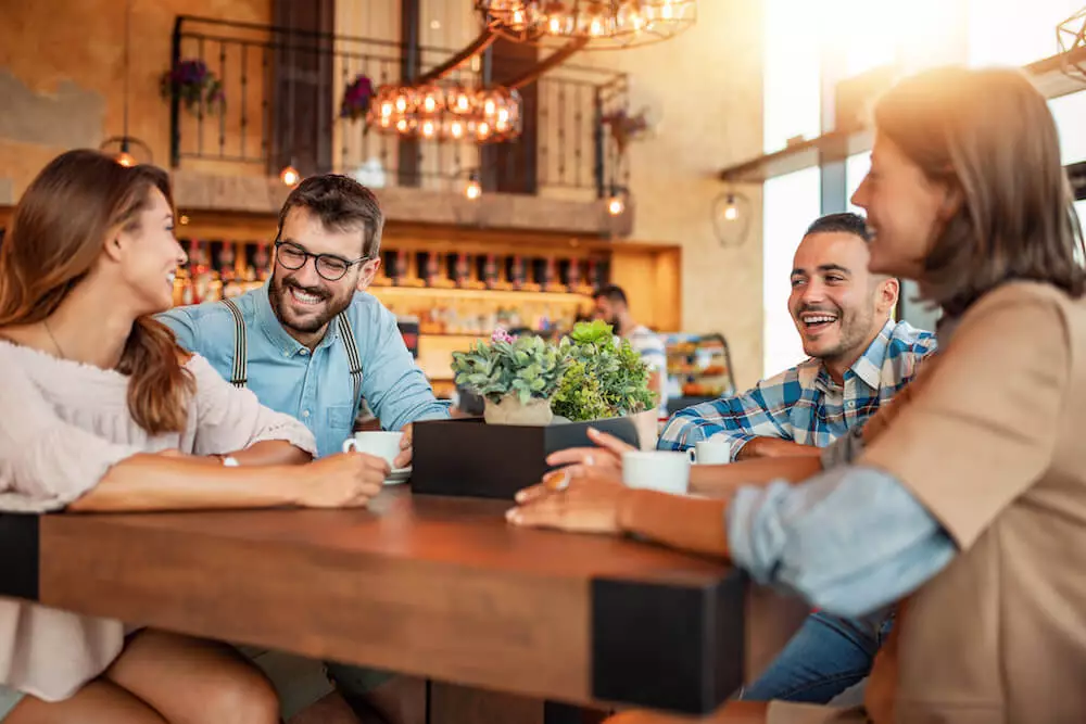 Mozrest - Group of friends sitting at a table in a restaurant, smiling and speaking together