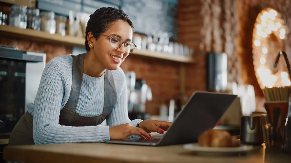 Mozrest - Smiling restaurant staff manager creating a Facebook business profile on her laptop