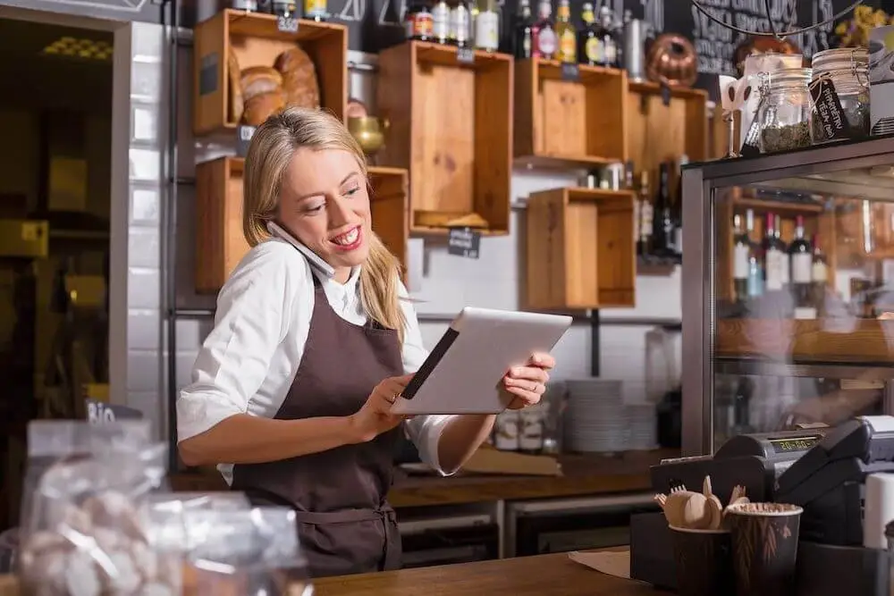 Mozrest - Personnel de restaurant souriant utilisant une tablette tout en étant au téléphone.