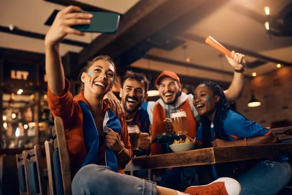 Four rugby fans watching the Six Nations in a pub are taking a selfie with their mobile phone to post it on social media.