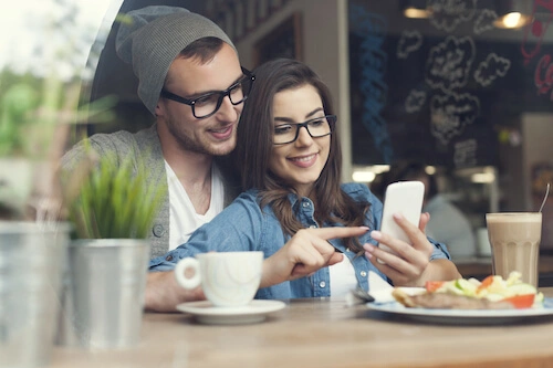 Couple in a restaurant searching for the next restaurant to book on their mobile phone