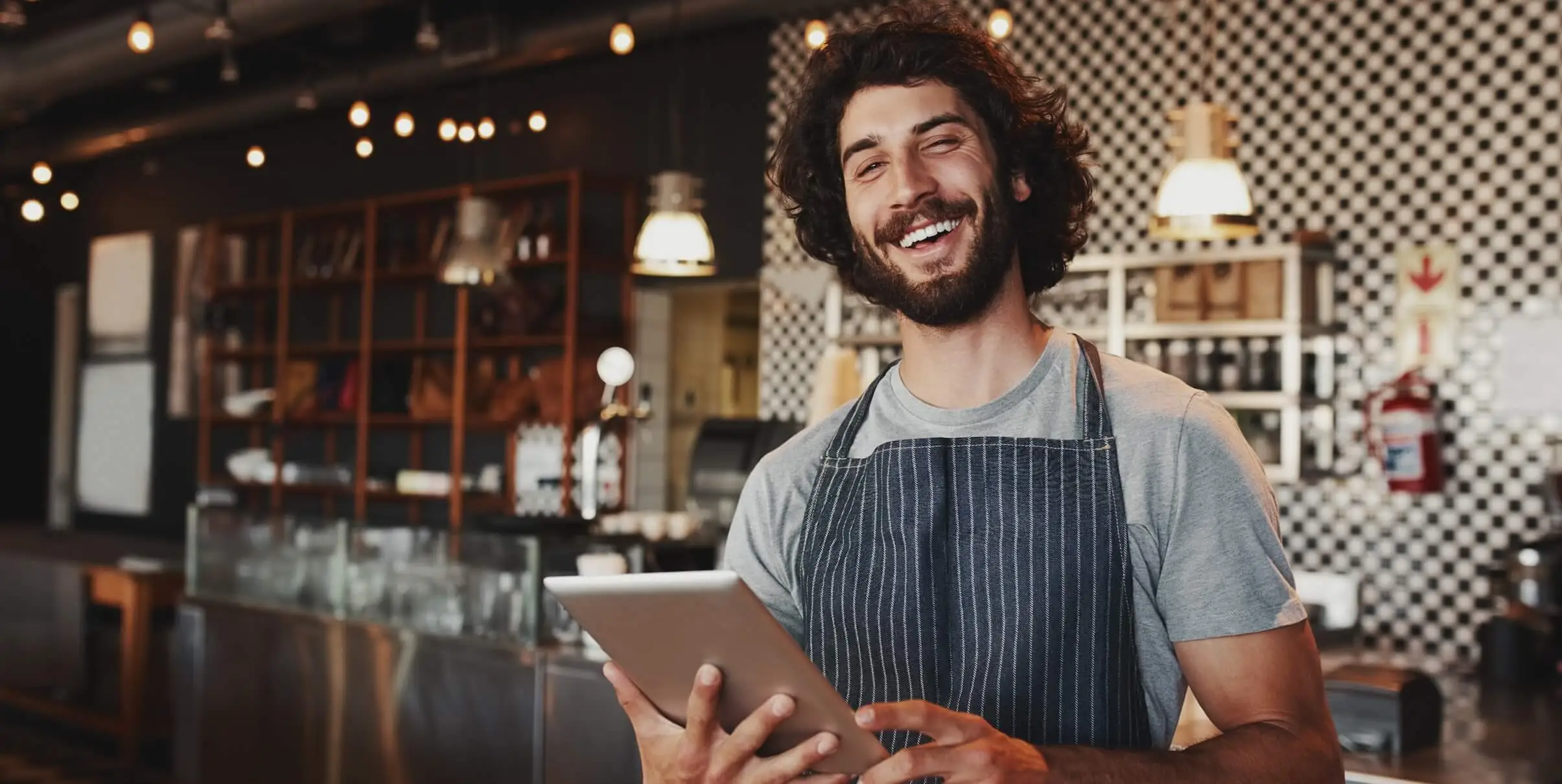 Mozrest - Solutions for Reservation Software - Restaurant manager smiling at us with a tablet to manage bookings in his hands