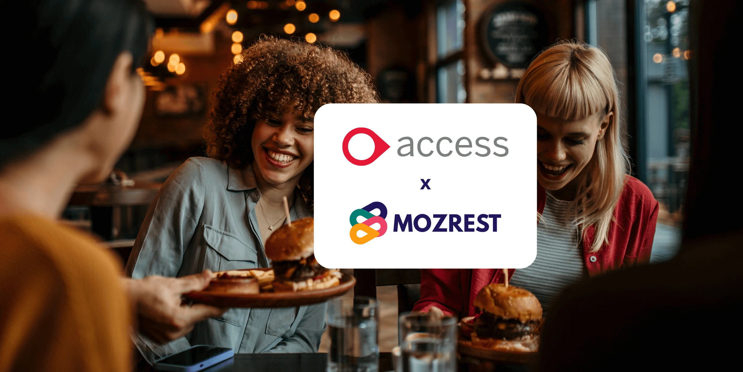 Mozrest - Solutions for Booking Channels - Group of friends seating at a table in a restaurant searching for a their next place to eat on their mobile phone