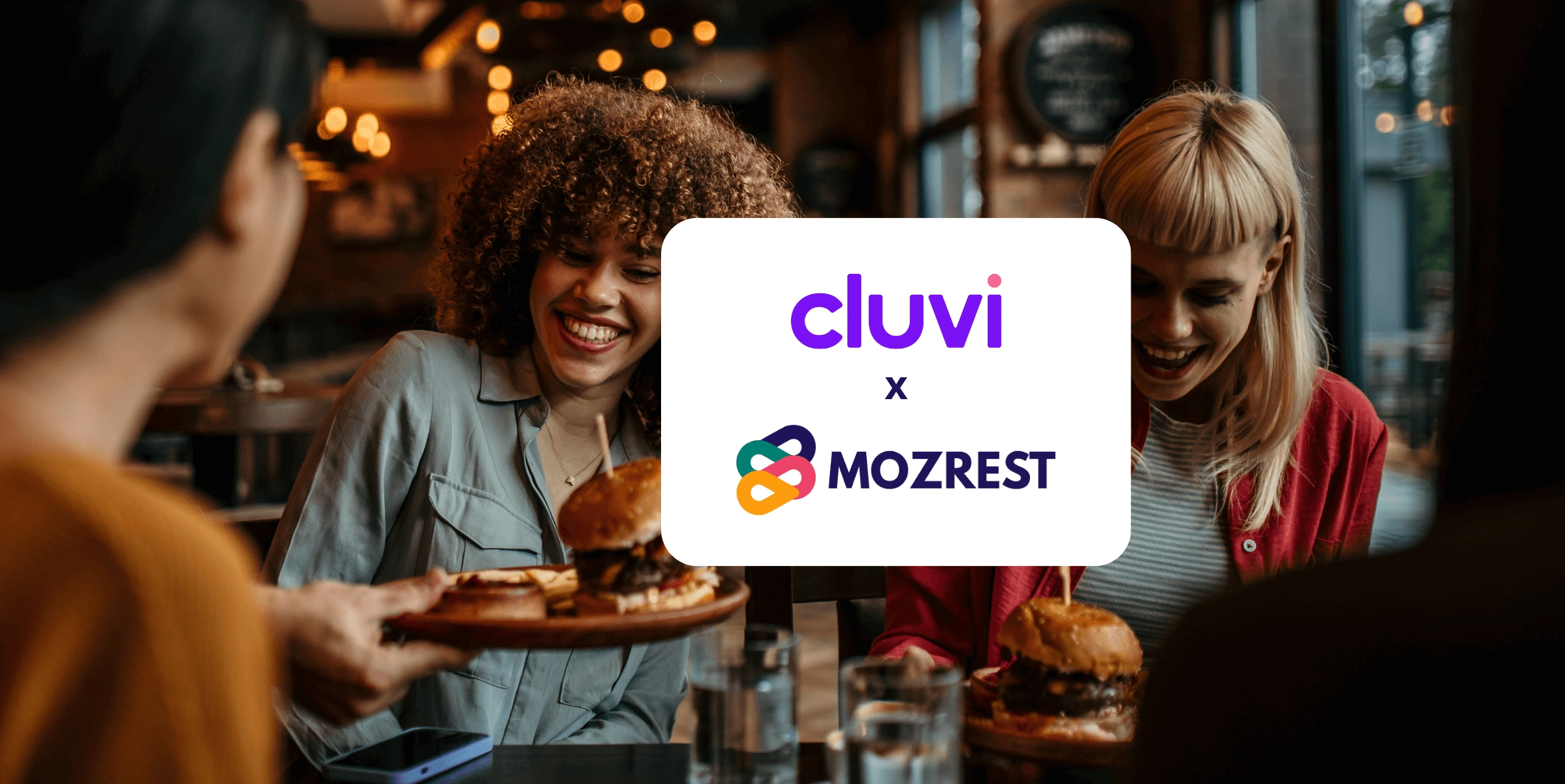 Mozrest - Solutions for Booking Channels - Group of friends seating at a table in a restaurant searching for a their next place to eat on their mobile phone