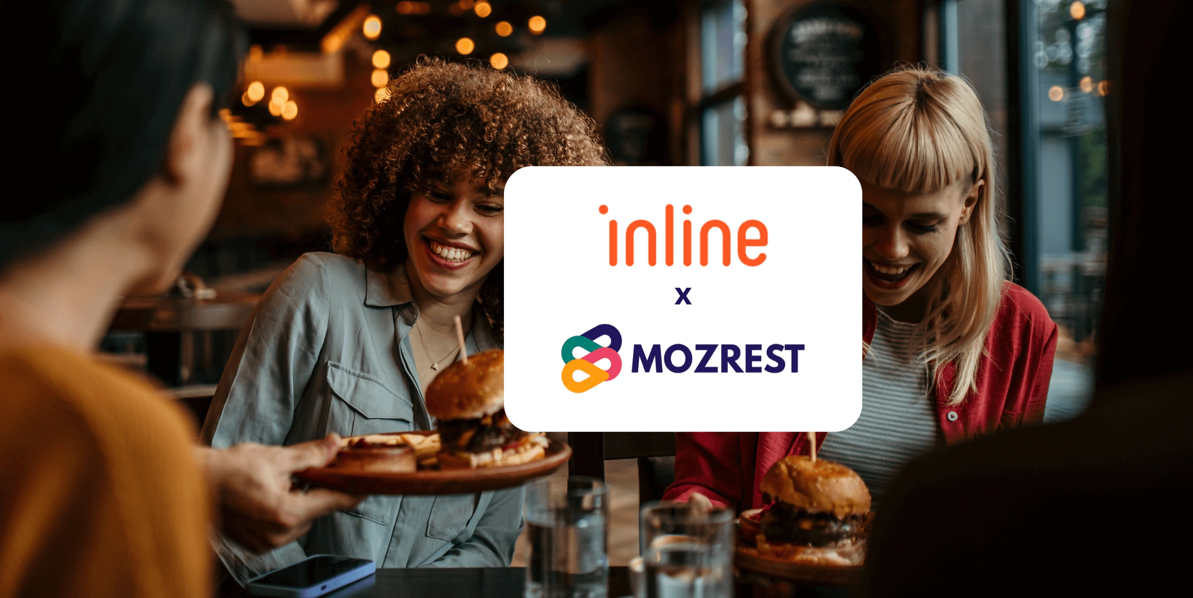 Mozrest - Solutions for Booking Channels - Group of friends seating at a table in a restaurant searching for a their next place to eat on their mobile phone