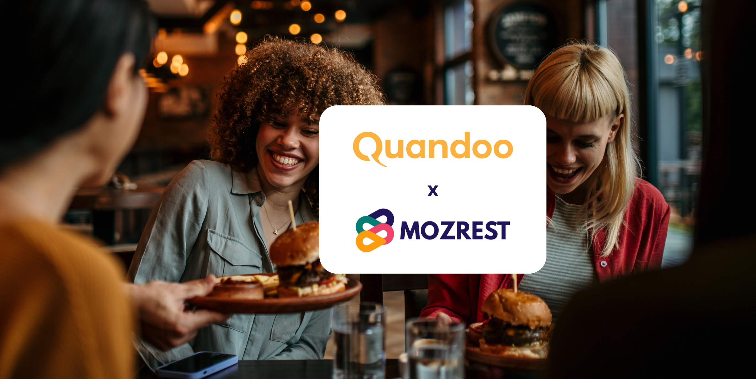 Mozrest - Solutions for Booking Channels - Group of friends seating at a table in a restaurant searching for a their next place to eat on their mobile phone