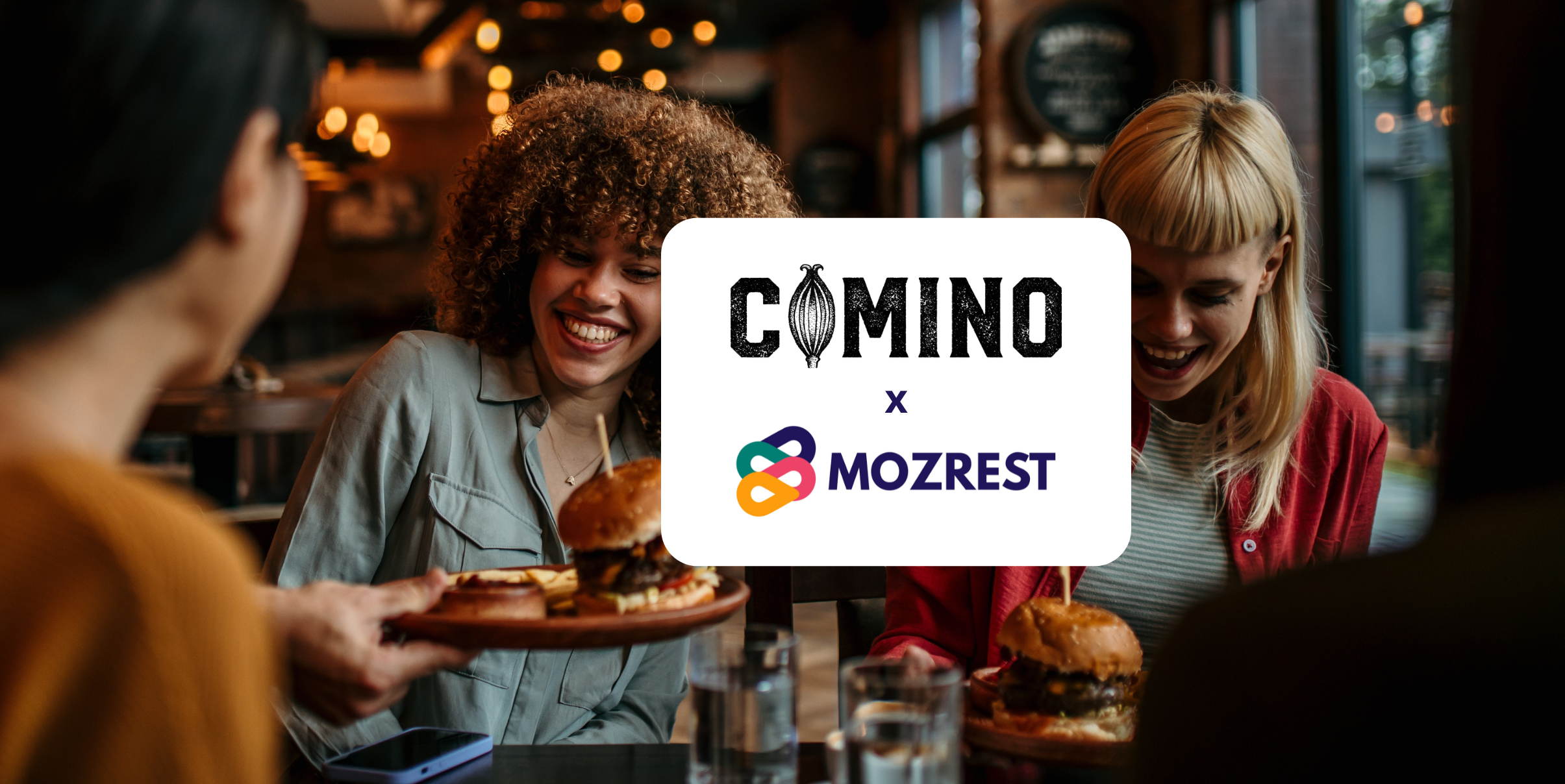 Mozrest - Lösungen für Buchungskanäle - Eine Gruppe von Freunden sitzt an einem Tisch in einem Restaurant und sucht auf ihrem Handy nach ihrem nächsten Restaurant.