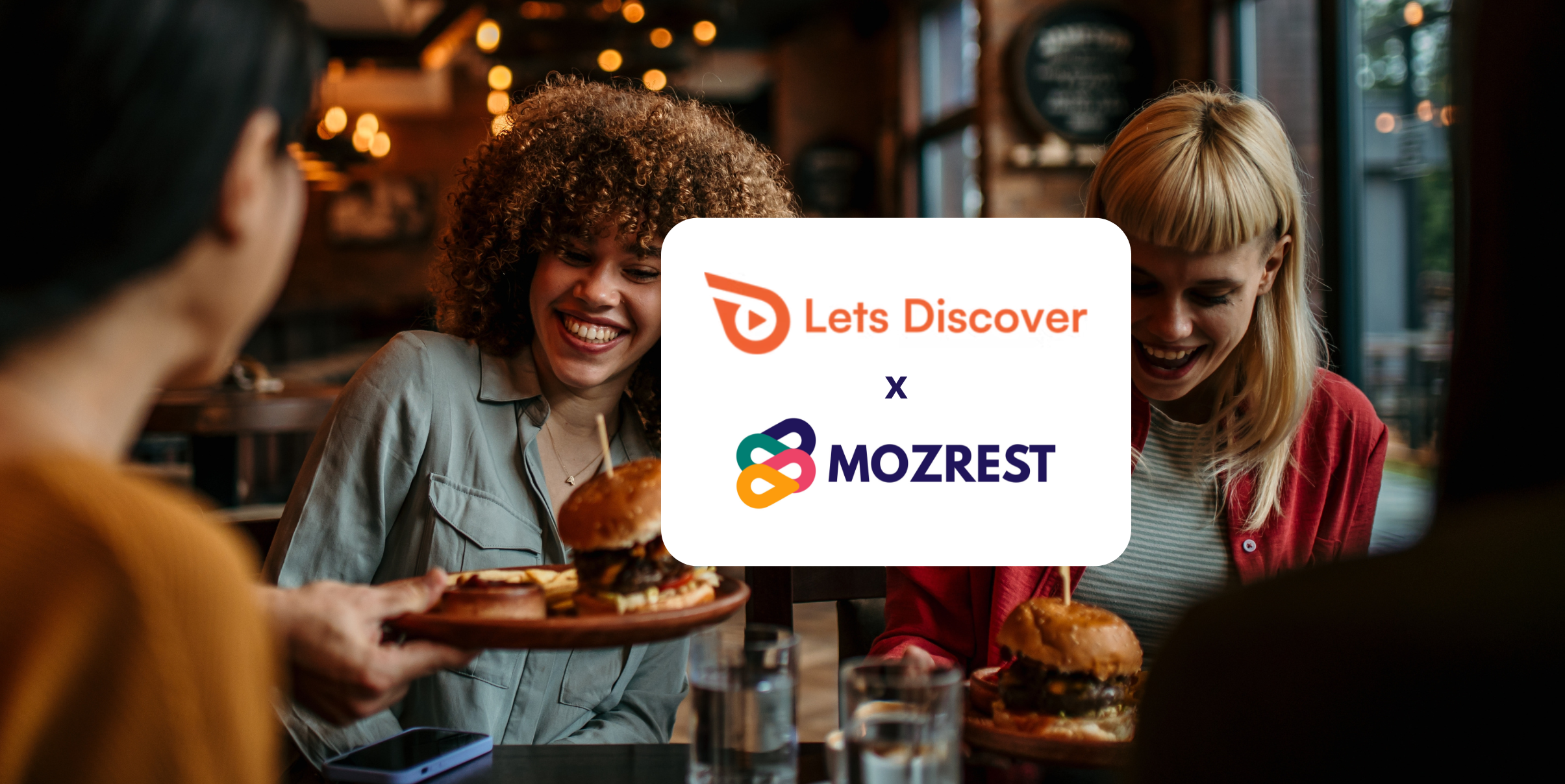 Mozrest - Lösungen für Buchungskanäle - Eine Gruppe von Freunden sitzt an einem Tisch in einem Restaurant und sucht auf ihrem Handy nach ihrem nächsten Restaurant.