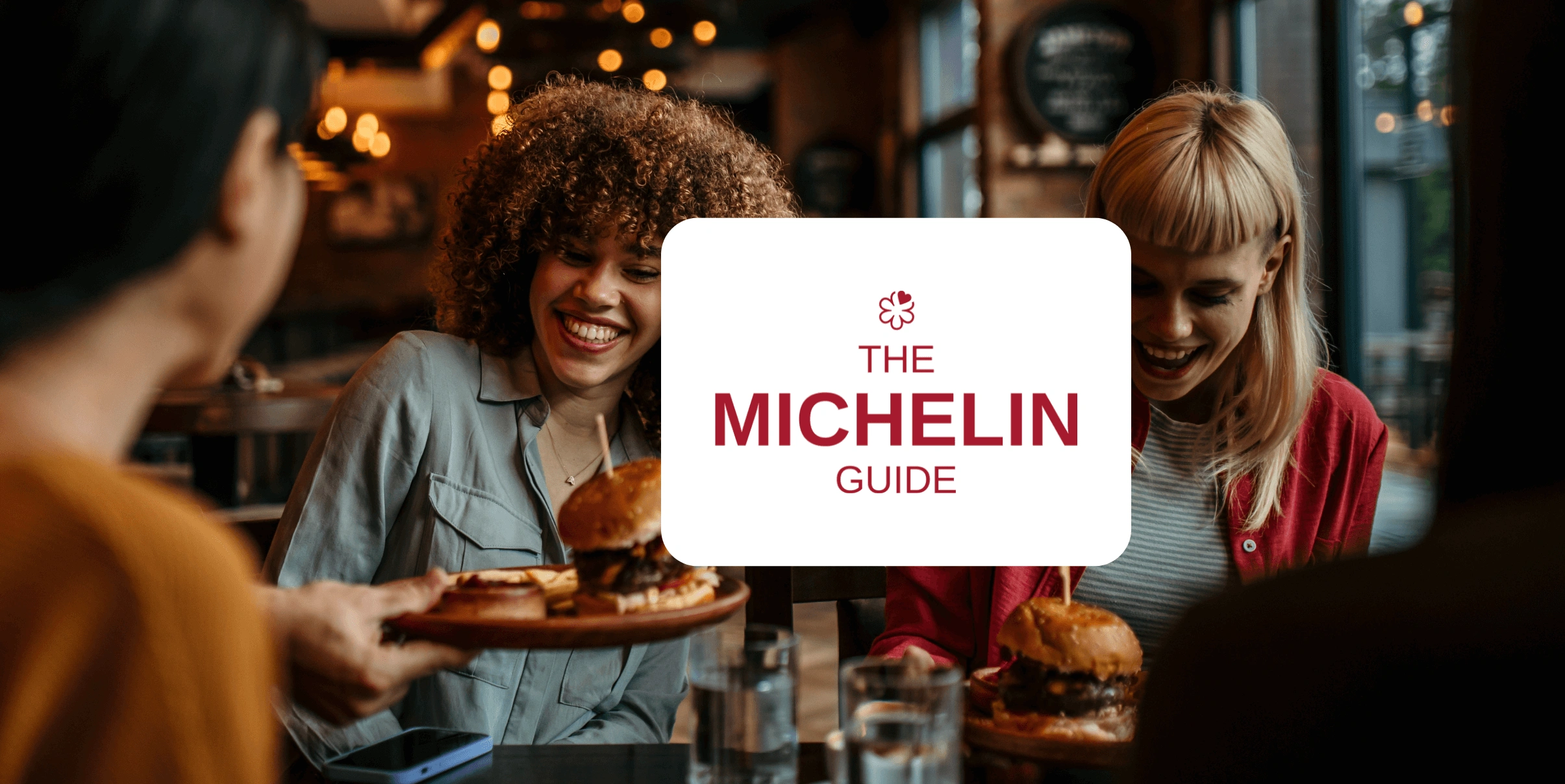 Mozrest - Solutions for Booking Channels - Group of friends seating at a table in a restaurant searching for a their next place to eat on their mobile phone