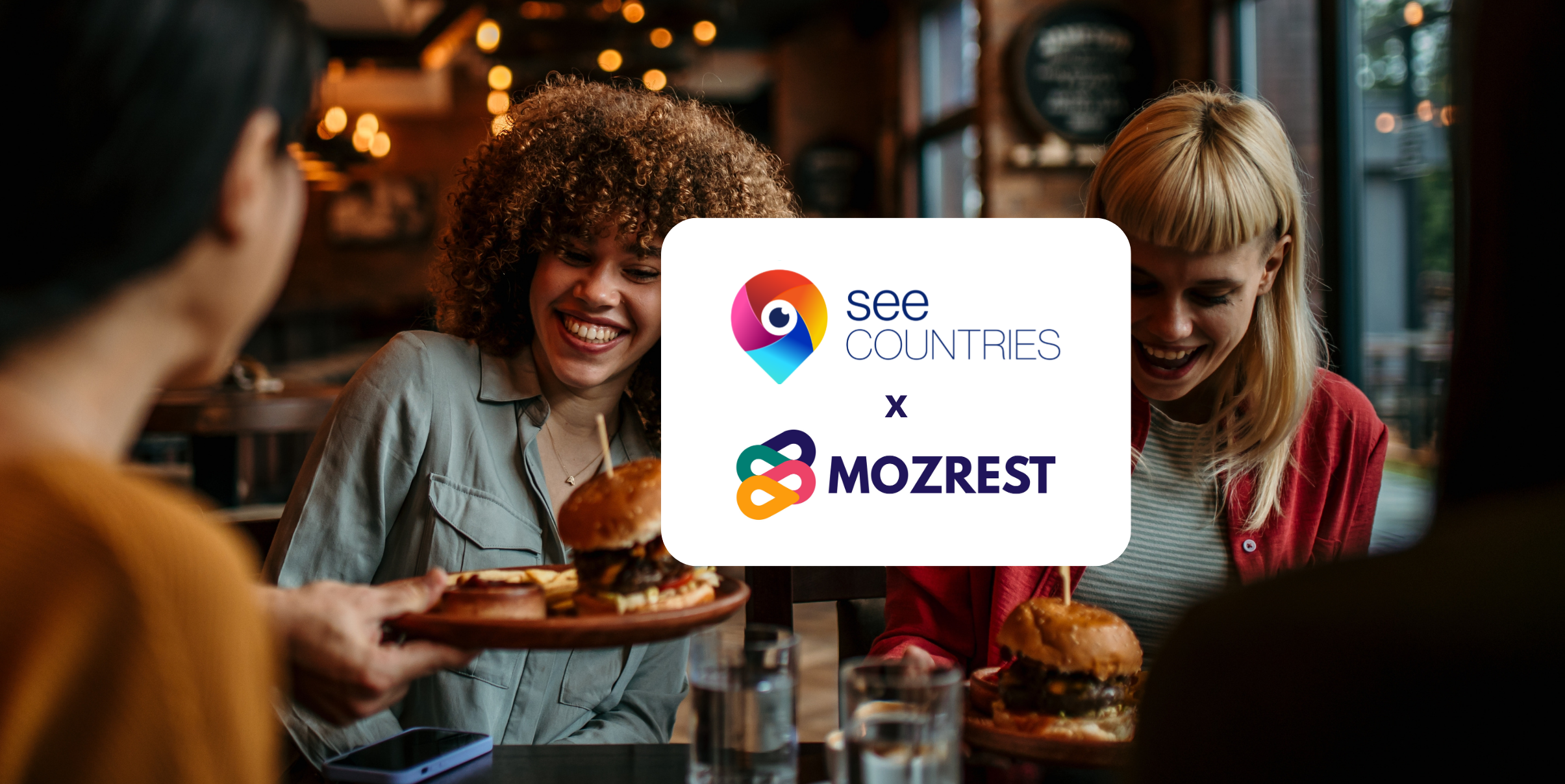 Mozrest - Lösungen für Buchungskanäle - Eine Gruppe von Freunden sitzt an einem Tisch in einem Restaurant und sucht auf ihrem Handy nach ihrem nächsten Restaurant.