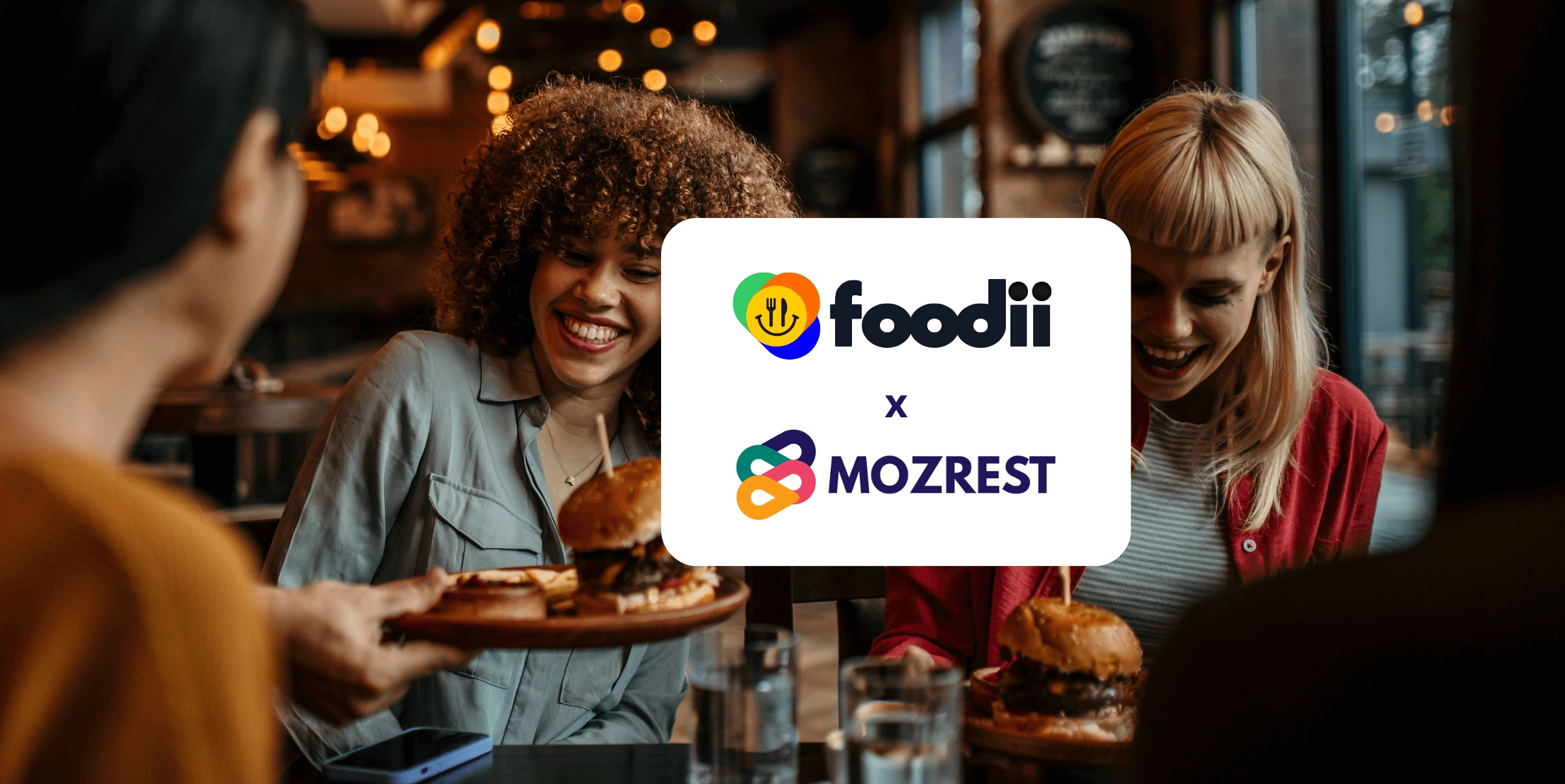 Mozrest - Solutions pour les Canaux de Réservation - Un groupe d'amis assis à une table dans un restaurant cherchant leur prochain endroit où manger sur leur téléphone mobile.