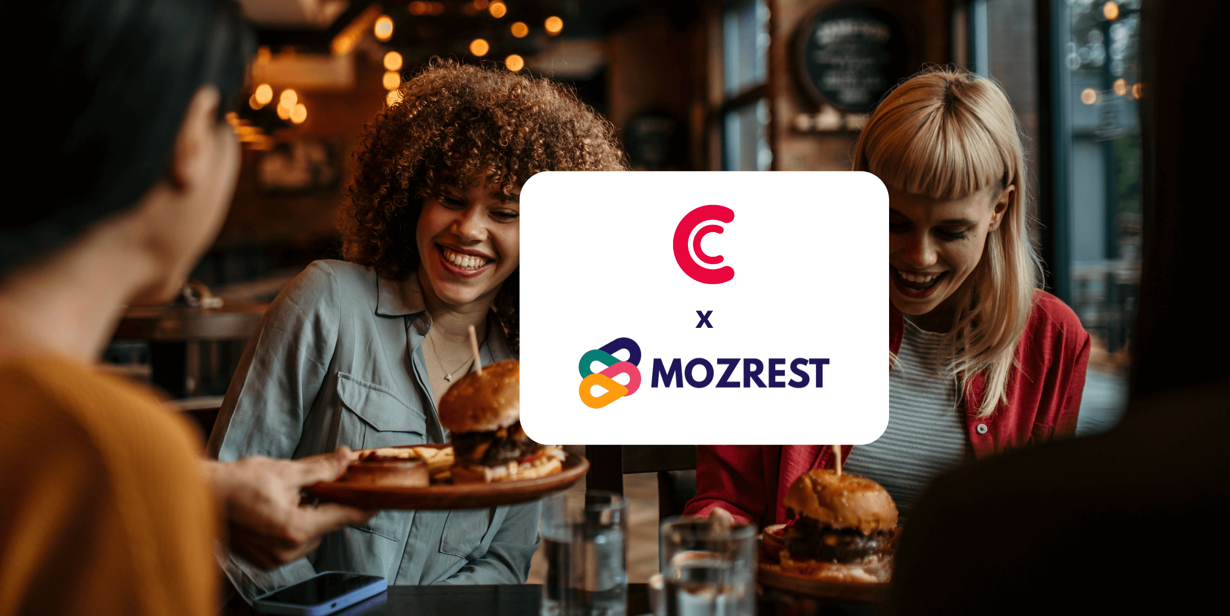 Mozrest - Solutions pour les Canaux de Réservation - Un groupe d'amis assis à une table dans un restaurant cherchant leur prochain endroit où manger sur leur téléphone mobile.